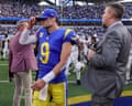 Quarterback Matthew Stafford adjusts his cap while walking past a man in a suit