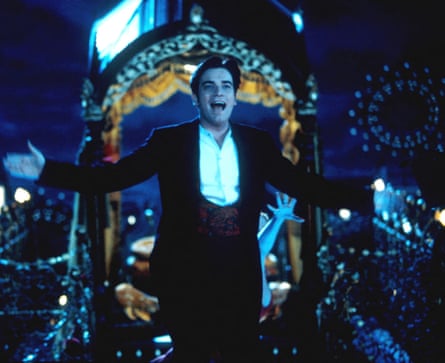 A man in a black tuxedo and white shirt with his arms full out, and smiling