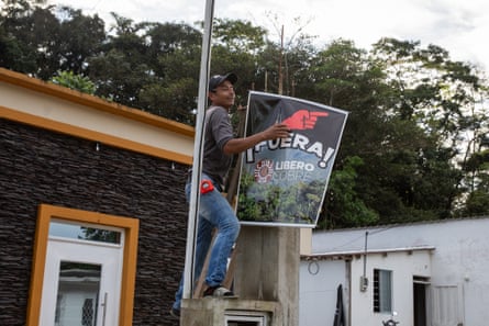 A man climbs on a building to puts up a sign that reads ‘Leave, Libero Copper!’ in Spanish