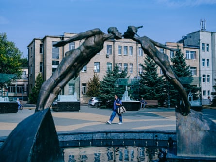 A statue of two people kissing, arched over a water feature