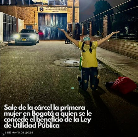 A woman on her knees in the street at night holds out her arms and looks up