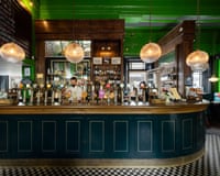 A bartender works behind a curved bar with many beer taps at the Old Ticket Office pub