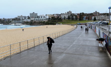 People walk along an empty Bondi beach foreshore