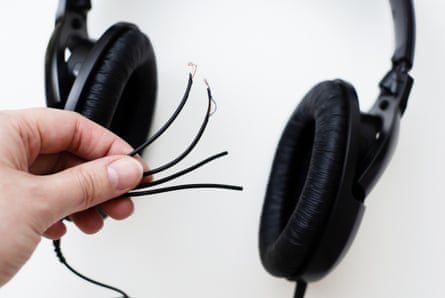 A person holding the frayed wires of a pair of headphones