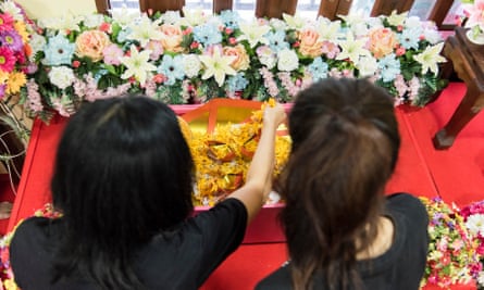 Phatcharakorn Likanrapichitkun (left) and her mother, Varunthip Manthin, place marigold flowers in a small casket containing their dog Fou Fou at Pet Funeral Thailand. The family dog was killed suddenly by a motorcycle in the early morning hours.