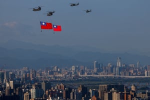 Four helicopters, two of them trailing huge Taiwanese flags, fly over a city skyline