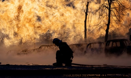 The silhouette of a firefighter kneeling with a bright fire in the background