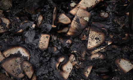 Burnt pages, with some words visible on the curled and charred pages, among ashes