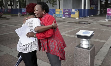Pamela Moses, a Black woman wearing a red and grey open-front sweater and gray slacks, hugs a woman outside Memphis City Hall in 2019.