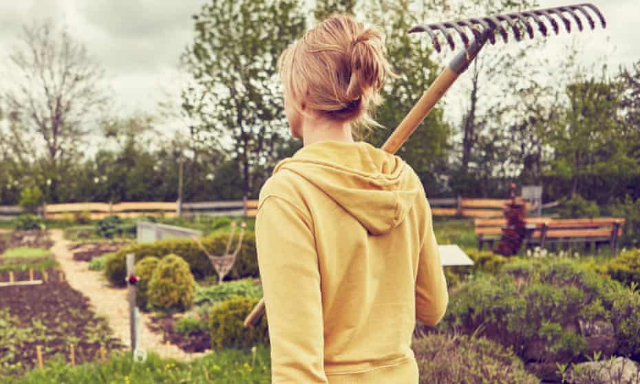 A woman carrying a rake