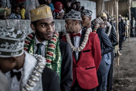 Men wearing ceremonial scarves and garlands of flowers perform a traditional dance