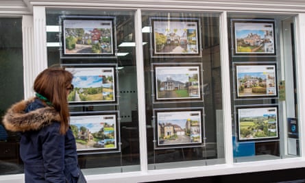 A woman looks in the window of an estate agents