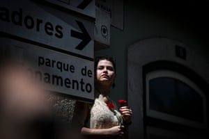 A woman holds a red carnation during a military parade in Lisbon