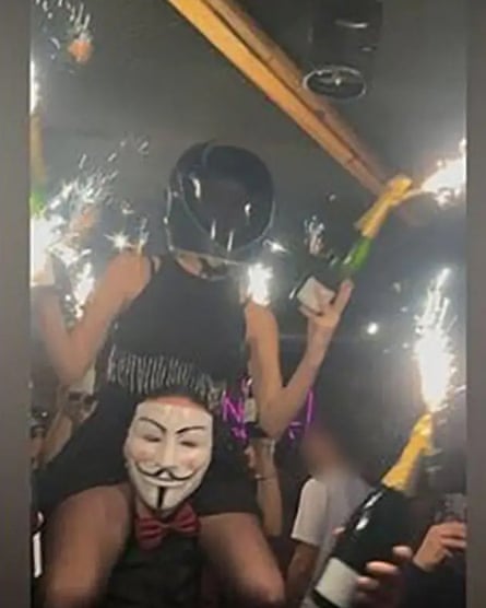 A woman in a helmet holding bottles with sparklers, sitting on the shoulders of someone wearing a mask. The image has been circulating online and appears to show the moment just before the ceiling caught fire. The image may have been subjected to some digital enhancement.