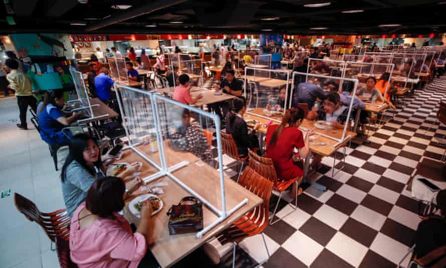 People eat lunch separated plastic screens, implemented to reduce the spread of Covid-19, at a food court in Bangkok