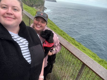 Gemma and Nic with a small black dog on a cliff walk