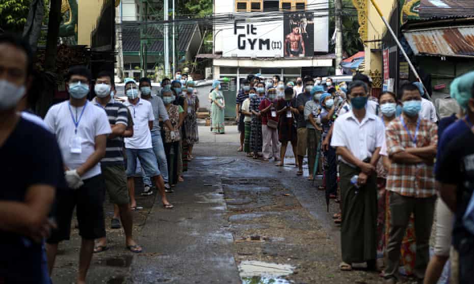 Voters wearing protective face masks line up to cast their ballots at a polling station in Yangon, Myanmar