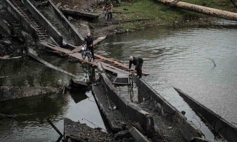 Men cross a destroyed bridge with thier bicycles in the frontline town of Bakhmut in Donetsk region.