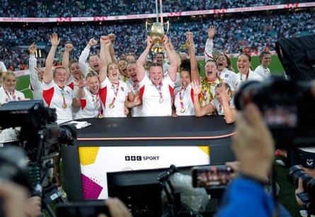 The victorious England team, led by prop Sarah Bern with the trophy, storm the BBC pitchside studio