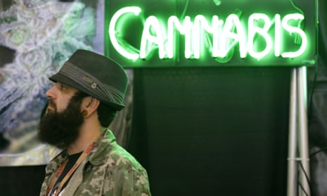 Adam Dunn, owner of the marijuana seed company T.H. Seeds, stands near a neon "cannabis" sign as he works in a booth for the pot-seed broker SeedsHereNow.com, Thursday, Feb. 19, 2015, at CannaCon, a marijuana business trade show in Seattle featuring exhibitors offering everything from grow lights to mechanical pot plant trimmers