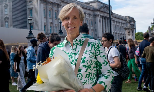 Julie Sanders holding flowers outside Buckingham Palace