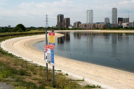Dry, sandy banks around the reservoir with tall buildings in the background.