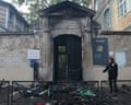 A police officer stands next to the burn-out entrance of Roger Verlomme secondary school following a blockading action by protesting students