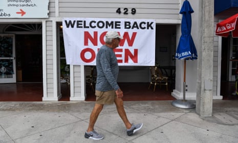A man walks past a sign reading ‘Welcome back, now open’ in Fort Lauderdale, Florida.
