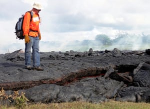 A geologist stands on a partly cooled section of lava flow