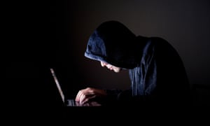 hooded male sits at laptop