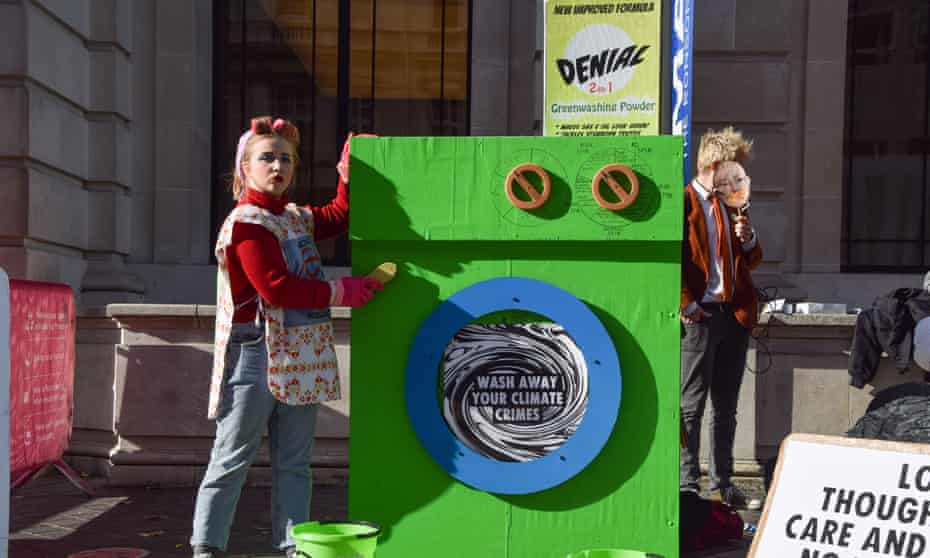 A protester in London dressed as a ‘scrubber’ with her ‘greenwashing machine’: ‘wash away your climate crimes.’ 