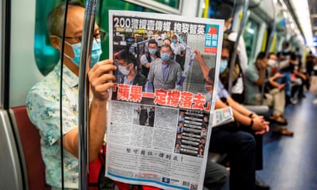 A commuter reads a copy of the Apple Daily newspaper.