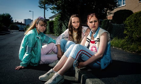 Scene from the drama shows three girls in casual clothing sitting on kerbside in a residential street