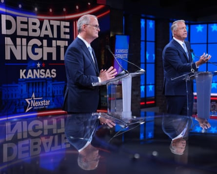 Two men at lecterns with a sign saying ‘Debate Night Kansas’ behind them