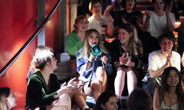 Participants in Nightwalks with Teenagers, a global social art experiment that sees teenagers lead adults on a tour of their city. Teens sitting on the Rainbow Stairs; one girl is holding a megaphone and talking while the others look on and listen