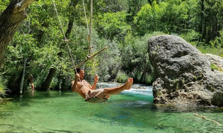 Man on swing over river in Spain