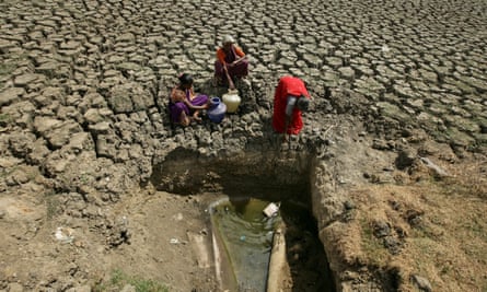 Women fetch water from a makeshift well at a dried-up lake in Chennai.
