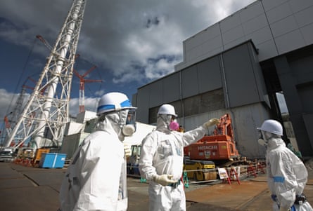 Workers stand outside reactor 4 as they continue the radiation decontamination process at the embattled Fukushima Daiichi nuclear power plant.