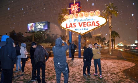 People take photos in front of the Welcome to Fabulous Las Vegas sign as snow falls.
