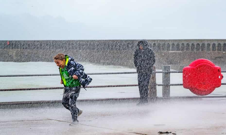 Two boys are soaked as waves slam against the harbour wall at Newhaven, East Sussex, UK.