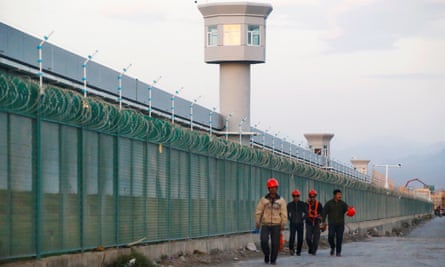 Workers walk by the perimeter fence of an ‘education centre’ in Xinjiang.