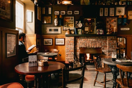 Man reading a book in a bar of the Harbourview Hotel, County Antrim