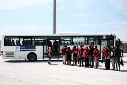 People queueing up to get on a bus with blankets around their shoulders