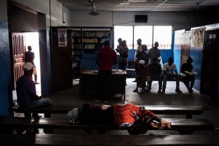 A woman lies on a bench in a health centre waiting room