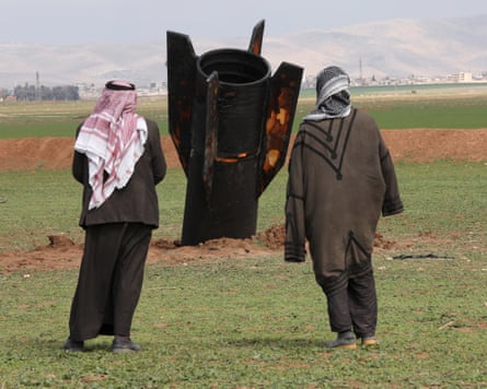 People stand next to an Iranian missile after it fell near Qamishli International airport, Syria