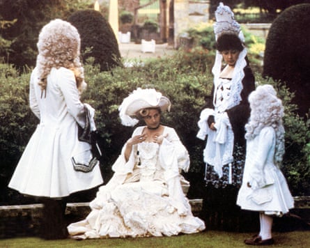 A group of people wearing elaborate period dress, in a garden