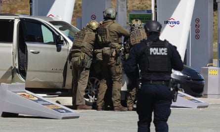 Royal Canadian Mounted Police officers surround the suspected shooter at a gas station in Enfield, Nova Scotia.