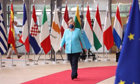 A masked Angela Merkel arrives walks along a red carpet in front of flags of European nations and the European Union at an EU summit in Brussels.