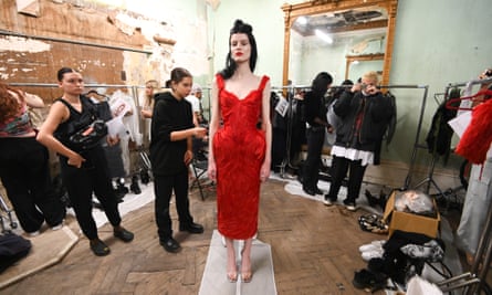 Un mannequin en robe rouge se tient dans les coulisses devant le défilé Dilara Findikoğlu lors de la fashion week de Londres 2022