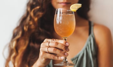 Pretty woman holding glass with tasty and cold kombucha. Healthy refreshment vegan drink<br>Unrecognizable defocused face on background. Summer beverage. Tasty and natural organic fermented juice.